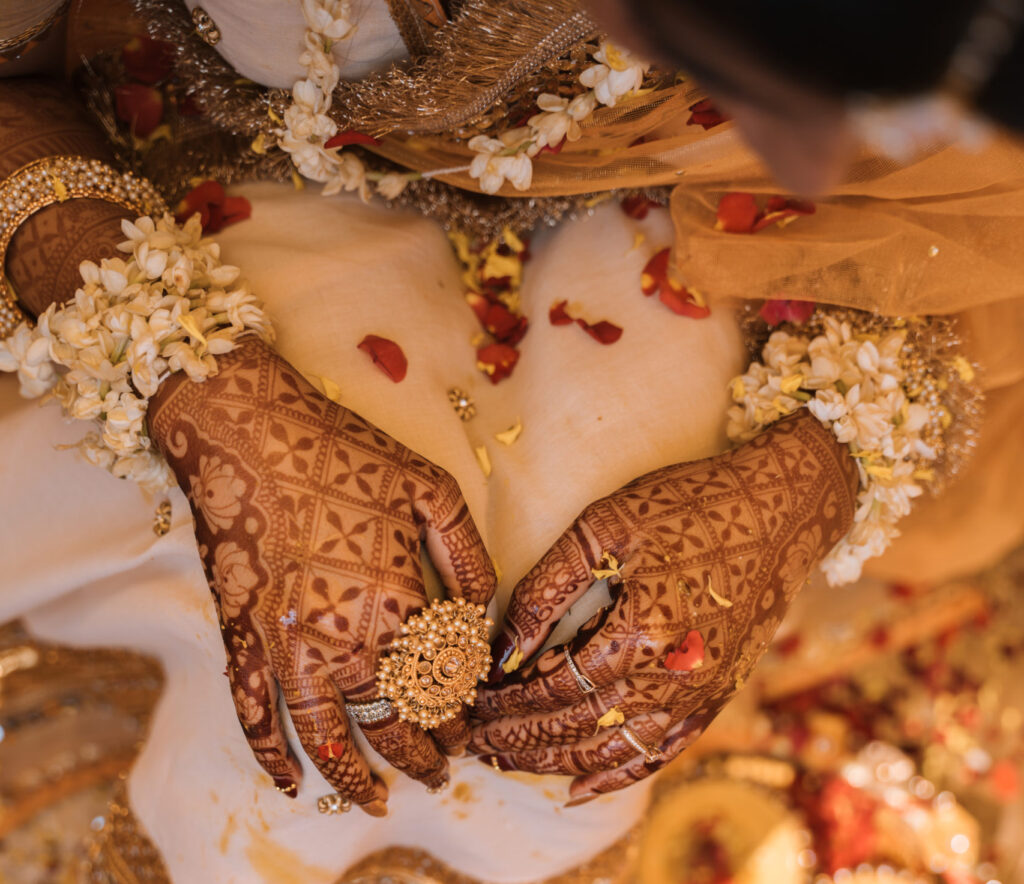 Best wedding photography capturing the vibrant haldi ceremony as the bride’s hands are adorned with traditional turmeric paste.